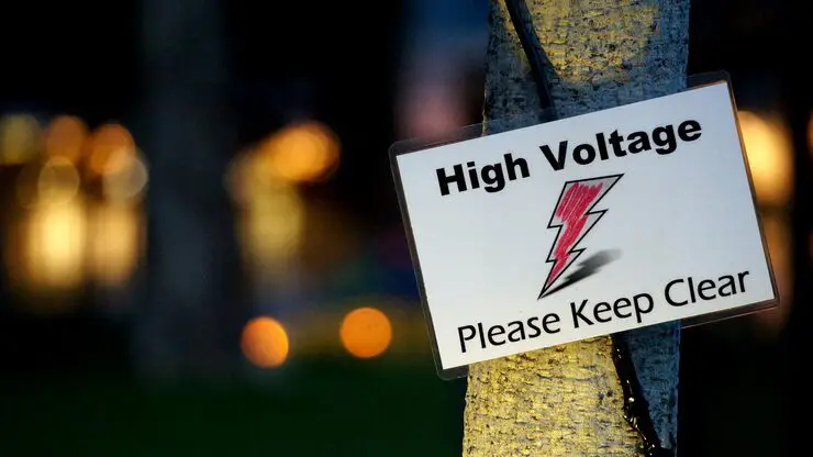 A warning sign reading "High Voltage Please Keep Clear" with a lightning bolt symbol.